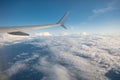 Wing of an airplane flying over white cloud in the sky during the vacation Royalty Free Stock Photo