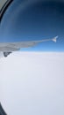 wing of airplane and the white clouds from above seen from the window porthole Royalty Free Stock Photo