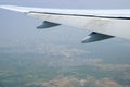 Wing of a jet liner with flaps down flying over polluted outskirts of Mumbai, India preparing to land