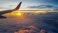 Wing of jet plane over the clouds at high altitude when sunset. Royalty Free Stock Photo