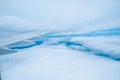 Wing of passenger jet flying between layers of white clouds. Royalty Free Stock Photo