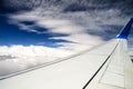 Wing of the plane against the sky and beautiful spindrift clouds. View through an airplane window. Royalty Free Stock Photo