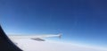 Wing of the plane and blue sky, above the white clouds image, from inside the window Royalty Free Stock Photo