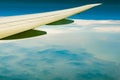 Wing of plane over mountain. Airplane flying on blue sky and white clouds. Scenic view from airplane window. Commercial airline Royalty Free Stock Photo