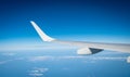 Wing of plane over white clouds. Airplane flying on blue sky. Scenic view from airplane window. Commercial airline flight. Plane Royalty Free Stock Photo