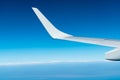 Wing of plane over white clouds. Airplane flying on blue sky. Scenic view from airplane window. Commercial airline flight. Plane Royalty Free Stock Photo