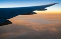 Wing of plane over white clouds. Airplane flying on sunrise sky. Scenic view from airplane window. Commercial airline flight. Royalty Free Stock Photo