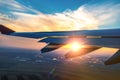 Wing of the plane on sunset sky background. Flying and traveling, view from airplane window on the wing on sunset time. Looking