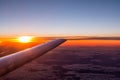 Wing view of airplane flying above the clouds in the sky at the sunset Royalty Free Stock Photo