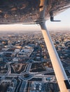 Wing view of a small plane flying at sunset over the city. Royalty Free Stock Photo