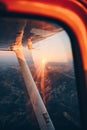 Wing view of a small plane flying at sunset over the city and the sea shore Royalty Free Stock Photo