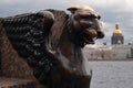 Winged lion on a cloudy spring day at the university embankment. Egyptian griffin on the background of the Neva River and St. Isaa