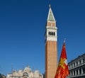 Winged Lion of St. Mark, the Venetian flag at San Marco square in Venice with the San Marco Campanile Tower.