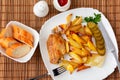 Wings of turkey baked with potato pieces on a white plate worth a bamboo napkin with tartar sauce and tomato sauce and Royalty Free Stock Photo