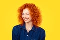 Winking. Closeup woman redhead curly hair smiling blinking eye to you camera isolated on yellow background. Happy life pictures, Royalty Free Stock Photo