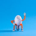 Winking Easter egg toy in the shape of a light bulb on a blu Royalty Free Stock Photo