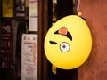 Winking emoji balloon hangs upside down outside a shop