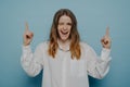 Winking happy teenage girl posing against blue wall