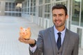 Winky businessman using piggybank to save money Royalty Free Stock Photo