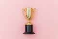 Winner or champion gold trophy cup on pink pastel colorful background