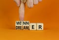 Winner or dreamer symbol. Concept words Winner or dreamer on wooden cubes. Businessman hand. Beautiful orange table orange