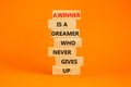 Winner or dreamer symbol. Wooden blocks with words A winner is a dreamer who never gives up. Beautiful orange table, orange