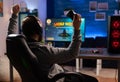 Winner gamer sitting on gaming chair at desk and playing space shooter video games Royalty Free Stock Photo