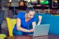 Winner girl euphoric watching a laptop in a coffee shop wearing a blue shirt Royalty Free Stock Photo
