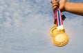 Winner hand raised and holding two gold medals with Thai ribbon