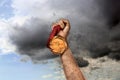 Winner raising hand with gold medal through dirt up to sky, closeup