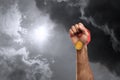 Winner raising hand with gold medal up to stormy sky, closeup. Space for text
