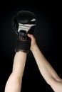 WinnerÃ¢â¬â¢s boxer hand raised in black boxing glove, closeup on dark background, copy space, victory concept Royalty Free Stock Photo