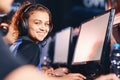 Side view of a happy mixed race girl, female cybersport gamer wearing headphones smiling at camera while participating