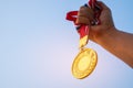 Winners Champion in success award concept : Woman hands raised holding gold medals with ribbon against blue sky background to show Royalty Free Stock Photo