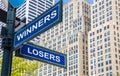 Winners losers crossroads street sign. Highrise buildings background Royalty Free Stock Photo