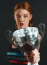 Winners never quit, quitters never win. Studio portrait of a sporty young woman holding a trophy against a black