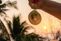 Winners success award concept. Silhouette woman hands raised and holding gold medals with Thai ribbon against sunset light sky Royalty Free Stock Photo