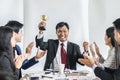 Winning business team with a man executive holding a gold trophy. Royalty Free Stock Photo