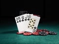 Winning combination in poker standing leaning on chips piles on green cover of playing table. Black background. Close-up Royalty Free Stock Photo