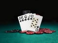 Winning combination in poker standing leaning on colored chips piles on green cover of playing table. Black background