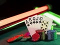 Winning combination in poker standing leaning on multicolored chips piles on green cover of playing table, under green Royalty Free Stock Photo