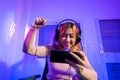 Happy Gamer playing video game online with smartphone she raises hands to wins