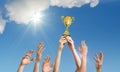 Winning team is holding trophy in hands. Many hands against blue sky Royalty Free Stock Photo