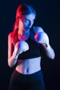 Winsome Active Female Boxer Posing in White Gloves And Making Hit Against Dark Background With Colorul Lights