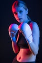 Winsome Active Female Boxer Posing in White Gloves And Making Hit Against Dark Background With Colorul Lights