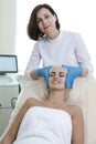 Winsome Caucasian Professional Cosmetologist Checking Young Female Human Skin Prior to Laser Treatment in Cosmetology Salon With
