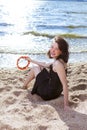 Winsome Happy Caucasian Brunette Girl in Casual Clothing Relaxing on Sandy Beach In Front of Sea Shore At Daytime Royalty Free Stock Photo