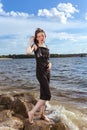 Winsome Relaxing Caucasian Brunette Girl Posing in Black Dress On Stone Line At Sea During Sunny Day