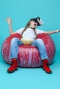 Winsome Teenager Female in Casual Clothing Using Modern Virtual Reality VR Helmet Eating Popcorn On Large Glass Bowl And Sitting