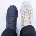 Winter activities - the photo shows two female feet - one in a black boot, the second leg is shod with old white figure skates Royalty Free Stock Photo